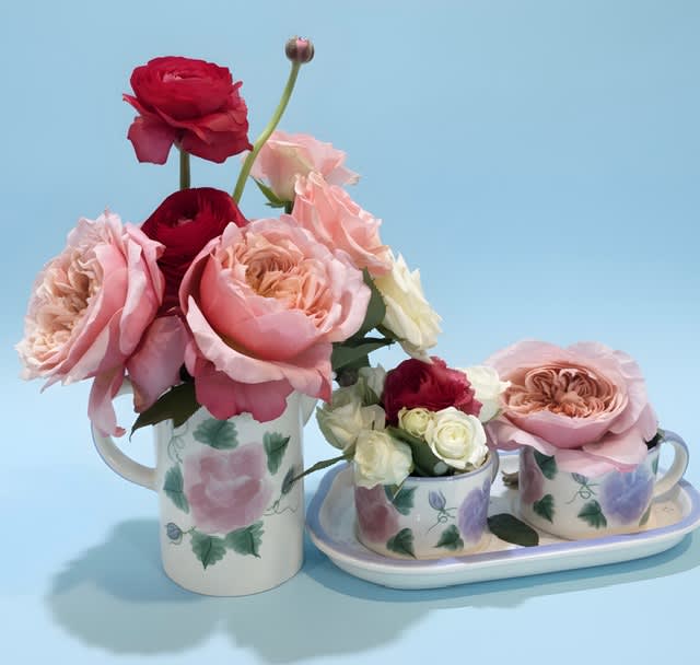 Pink and red roses arranged in floral mugs and a tray