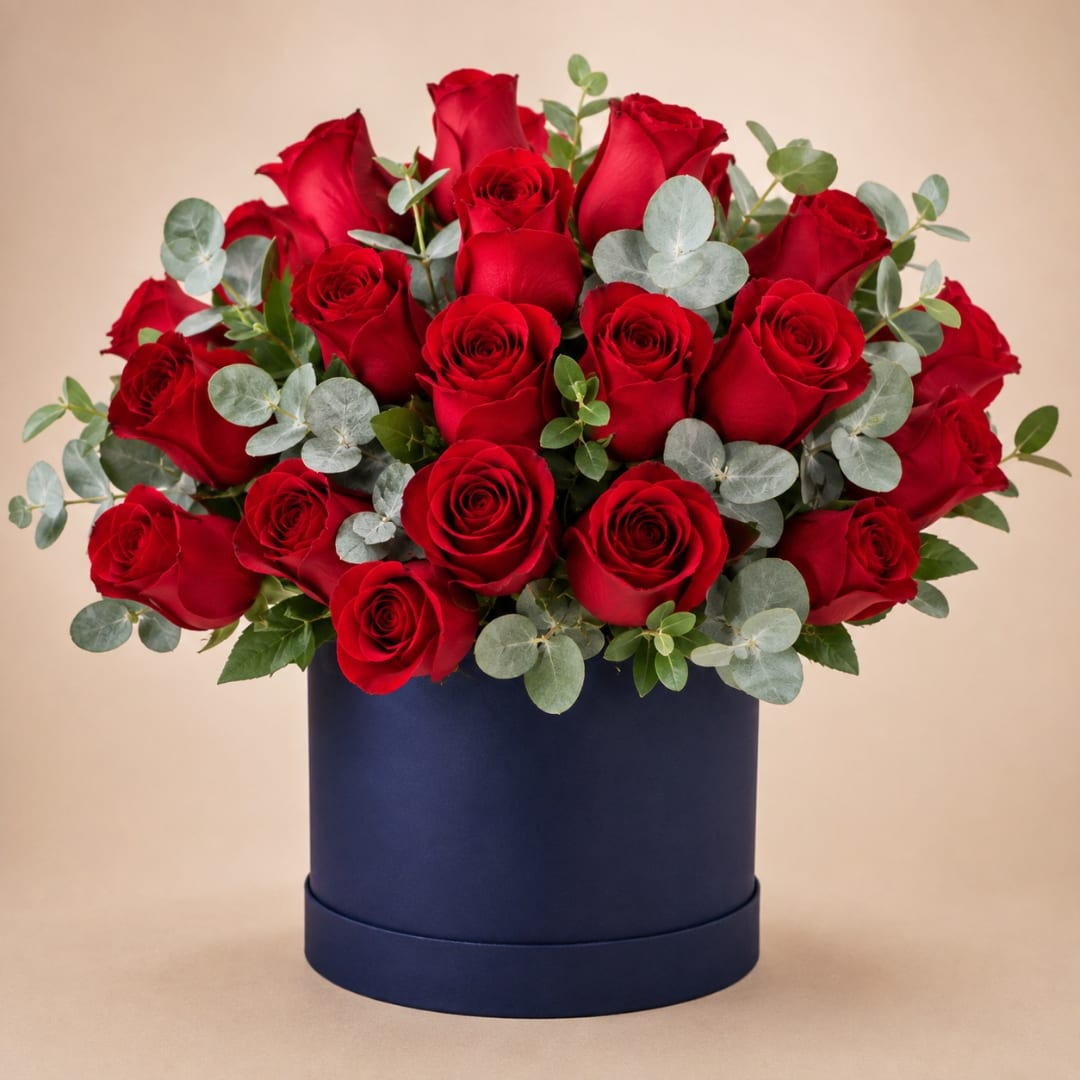 Red roses arranged in a navy round box with eucalyptus