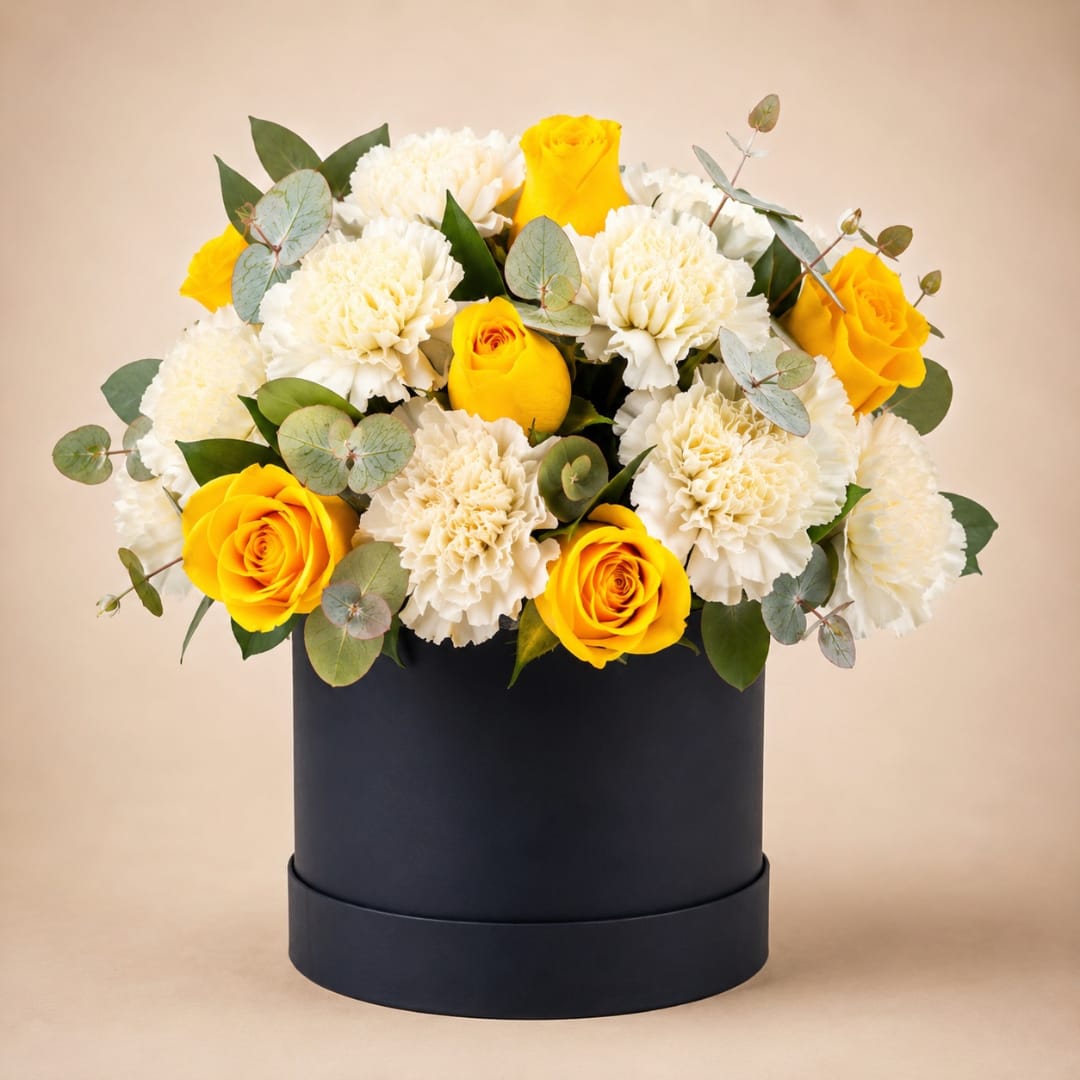 Yellow roses and white carnations in a black hatbox