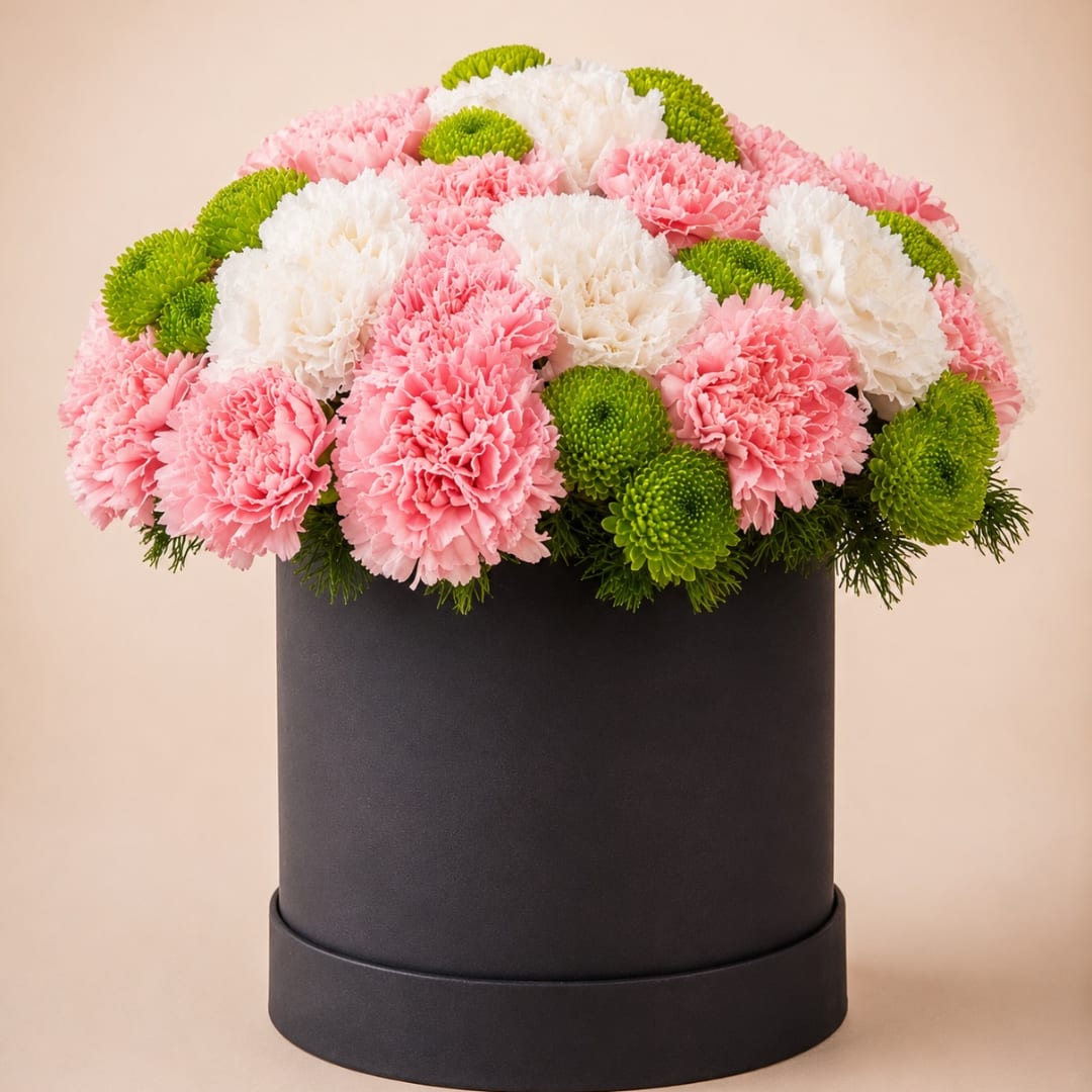 Pink and white carnations with green button mums in a black hatbox