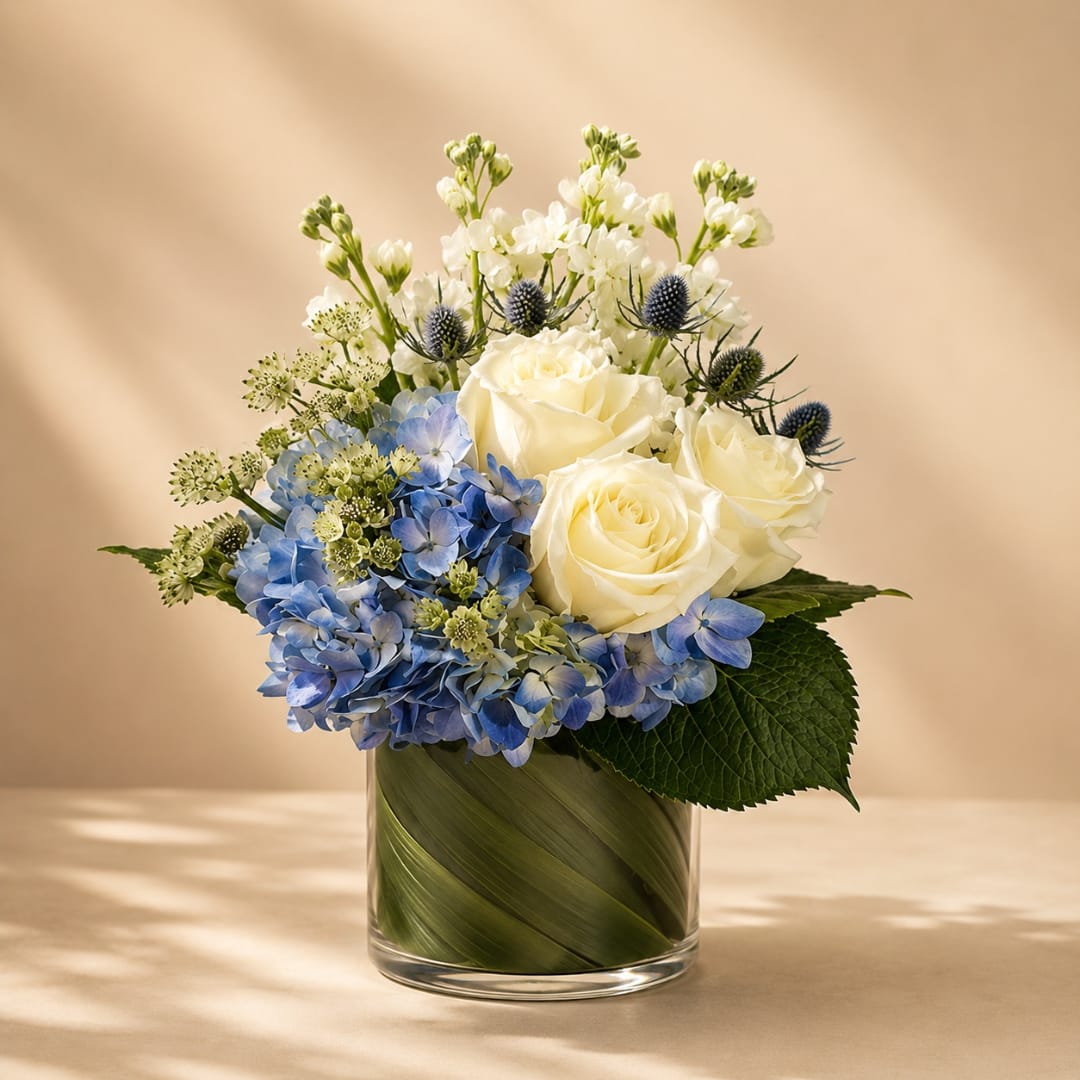 White roses and blue hydrangeas in a glass vase