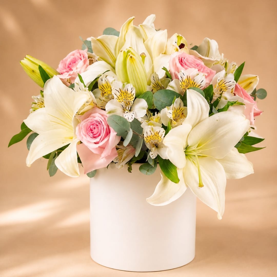 White lilies and pink roses arranged in a white vase