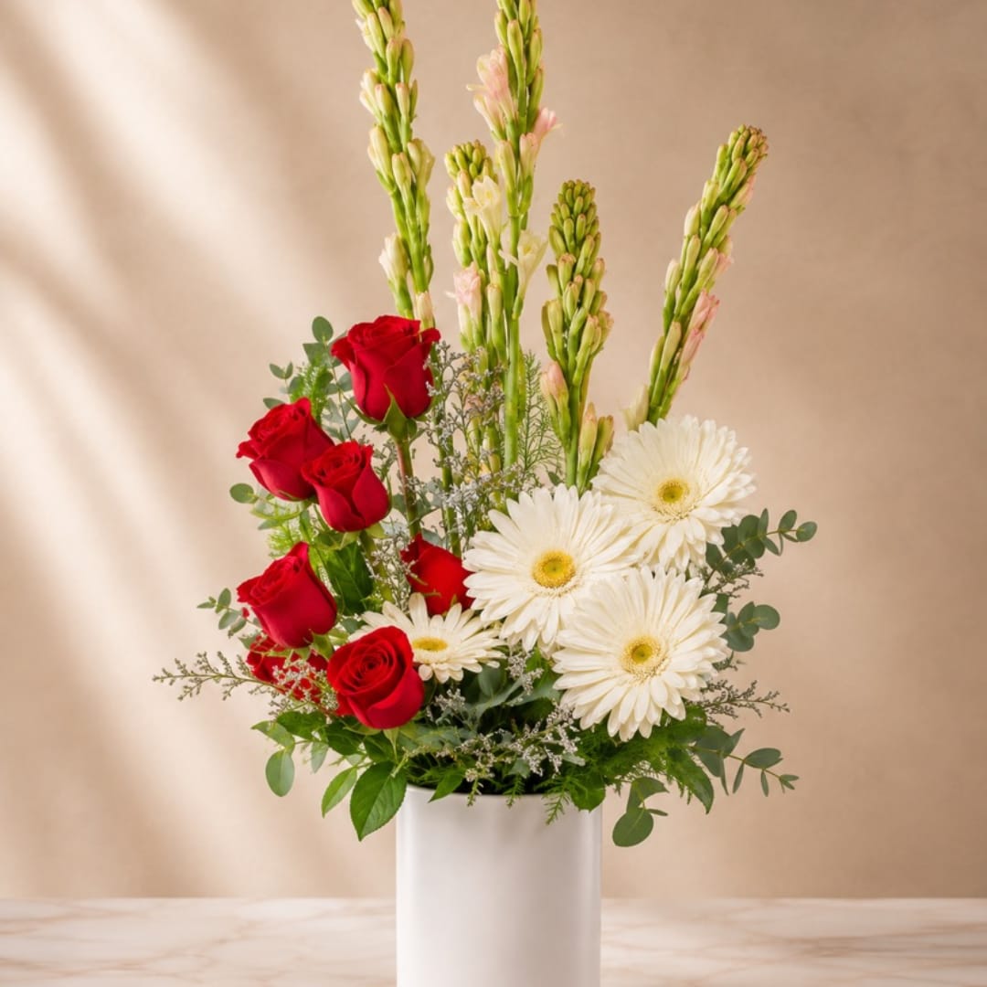 Red roses and white daisies in a white vase with tall pink flower spikes