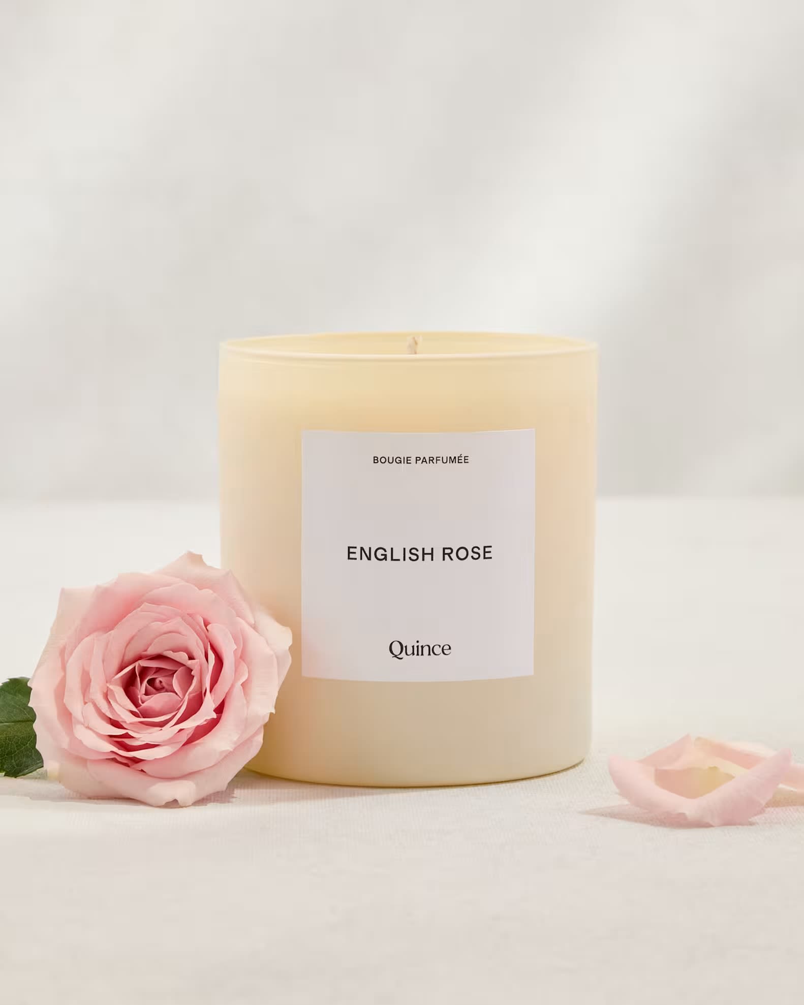 Rose Scented Candle - A soft, romantic gift that pairs the timeless appeal of roses with a gently scented home accent - this rose scented candle is perfect as a love and romance gift or a thoughtful "just because" surprise. The cream-colored candle sits in a simple cylindrical glass jar with a white "English Rose" label, and a pale pink rose placed beside it echoes the scent and visual theme so the recipient feels remembered and cherished.  Designed to read like an elegant keepsake, the palette of blush pink, warm ivory, and touches of yellow creates a calm, feminine presentation that suits birthdays, thank you gestures, or Mother's Day. The glass jar and clean label make it easy to display on a vanity or bedside table, while the rose fragrance fills a room with soft, floral notes that complement quiet evenings and relaxed mornings.  Give this when you want someone to feel genuinely seen - whether celebrating a milestone or sending a small token of appreciation. Available ready-to-gift; keep the wick trimmed to 1/4 inch and burn on a heatproof surface, allowing the scent to develop fully for a few hours on first use.