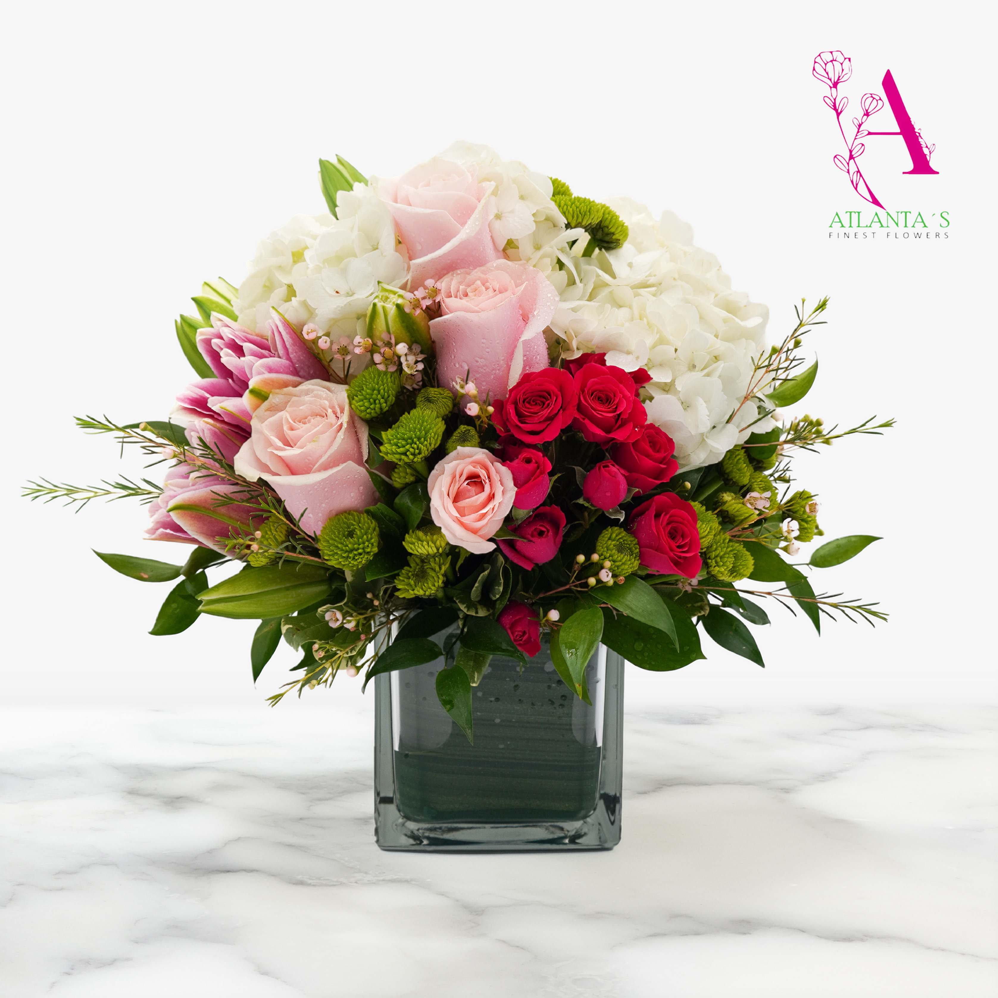 Mixed pink, red, and white flowers arranged in a square glass vase