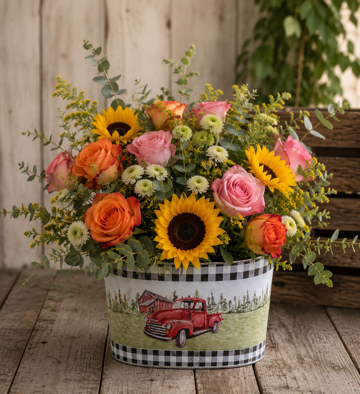 Mixed bouquet of roses and sunflowers in a decorative tin container
