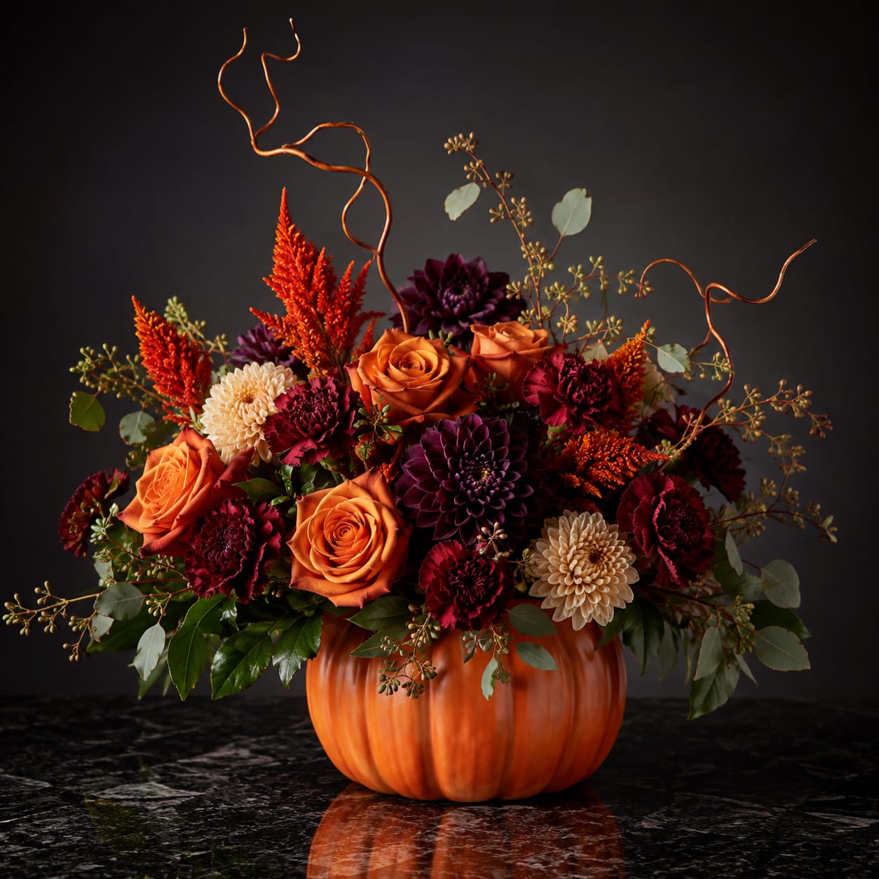 Orange and burgundy floral arrangement in a pumpkin-shaped container