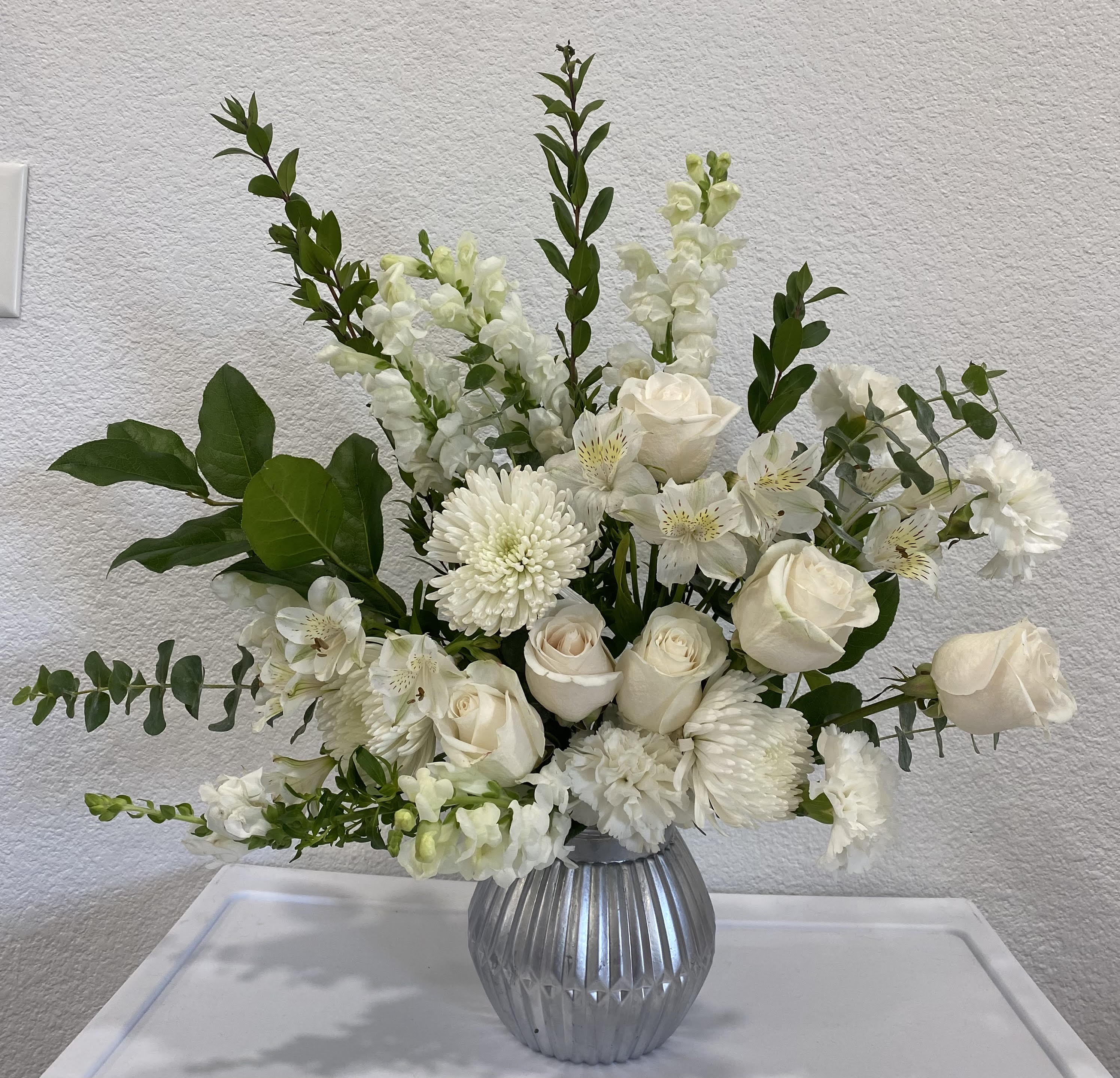 White floral arrangement in a ribbed silver vase