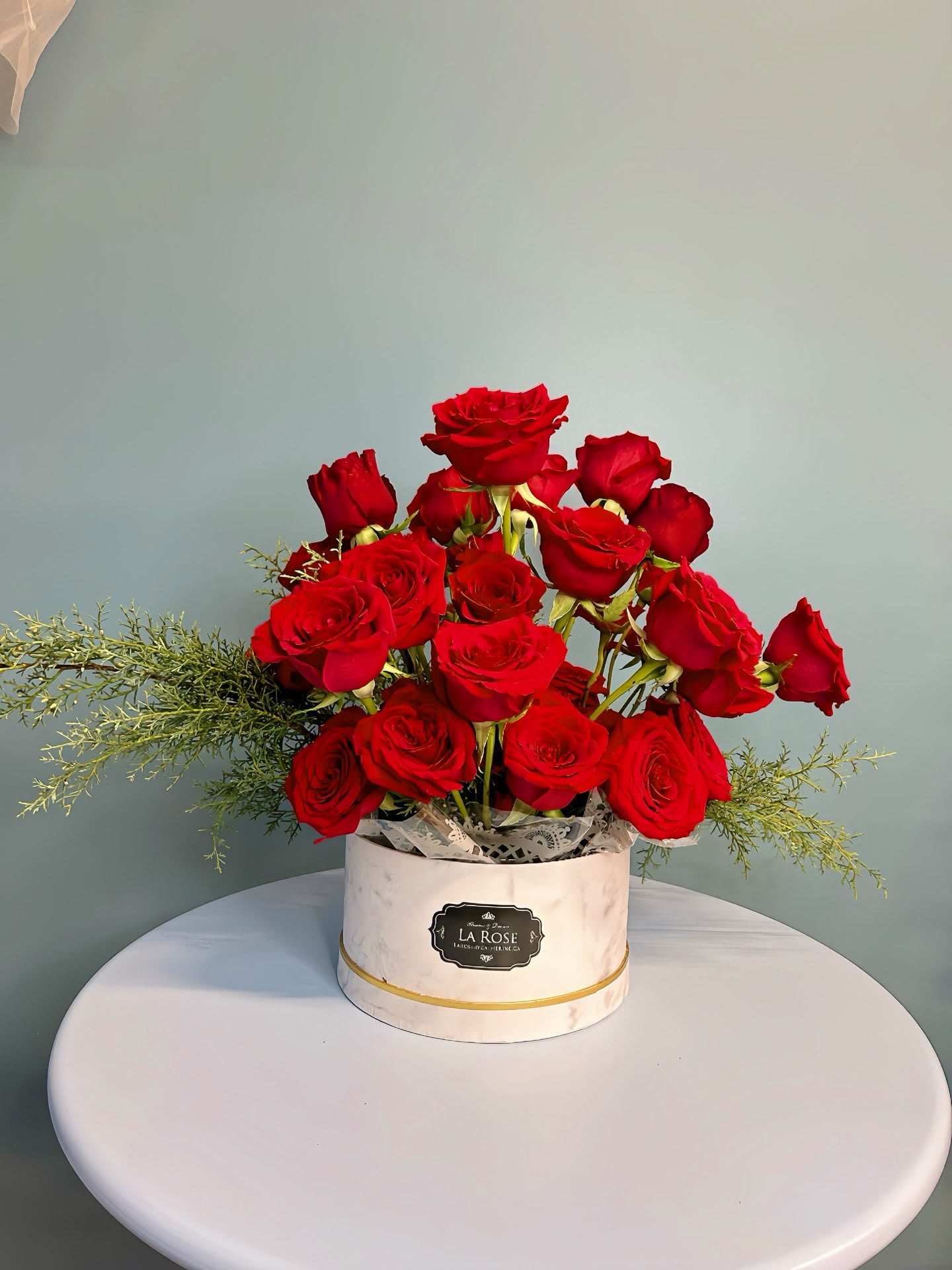 Red roses arranged in a white round box on a table