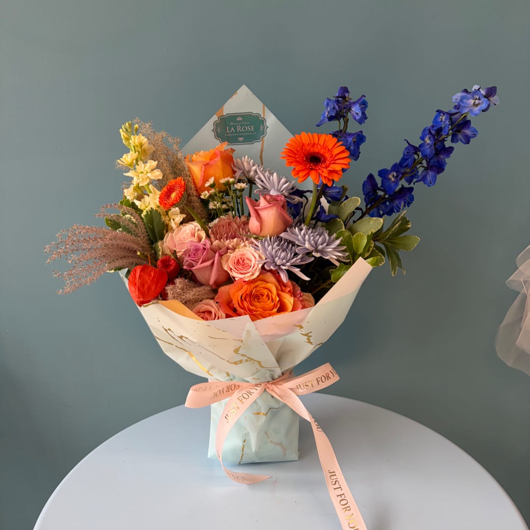 Bouquet of mixed flowers in pastel wrapping with a pink ribbon