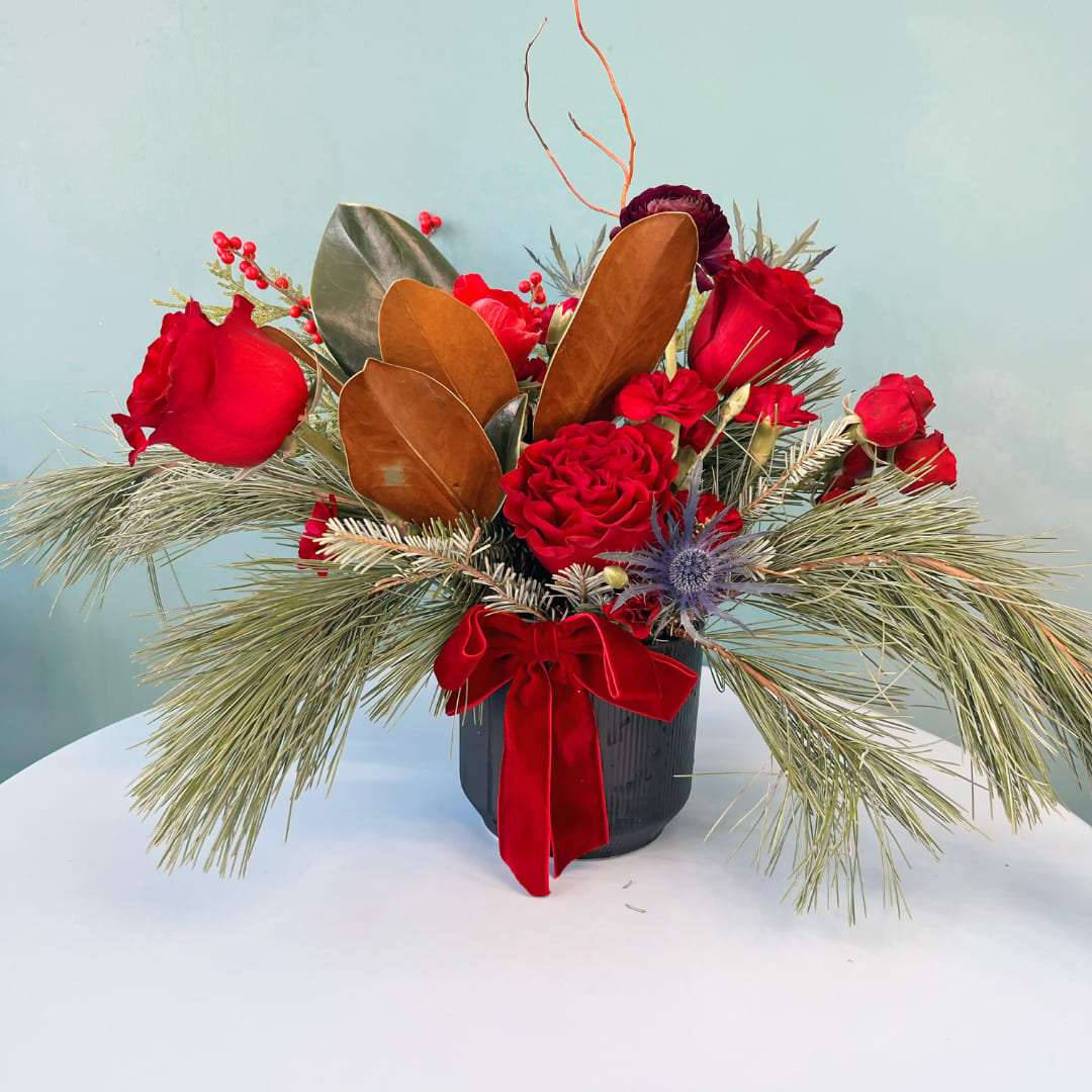 Red roses in a black vase with pine and a red ribbon