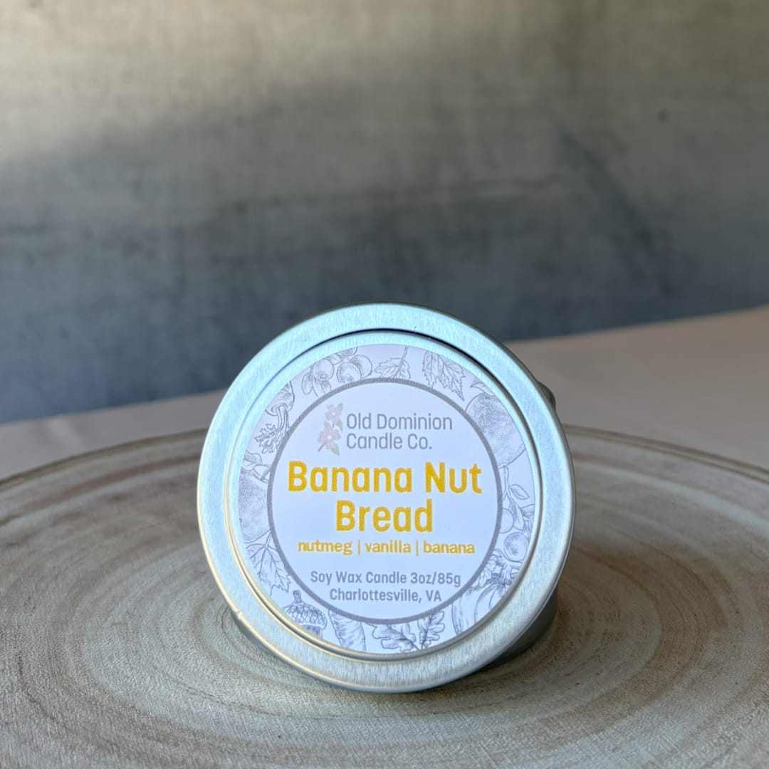 Small tin candle labeled Banana Nut Bread on a wooden surface