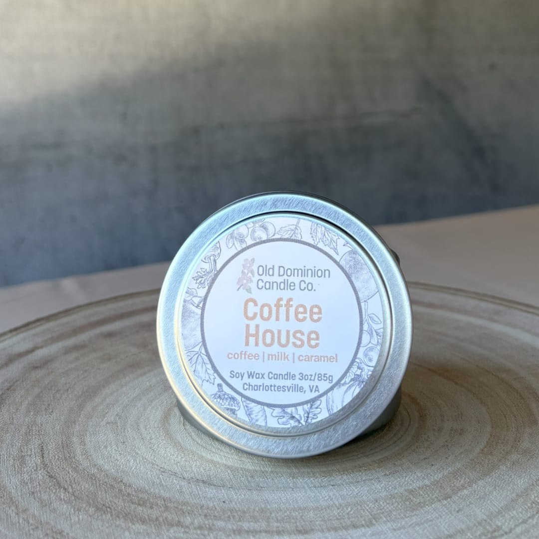 Small tin candle labeled Coffee House on a wooden surface