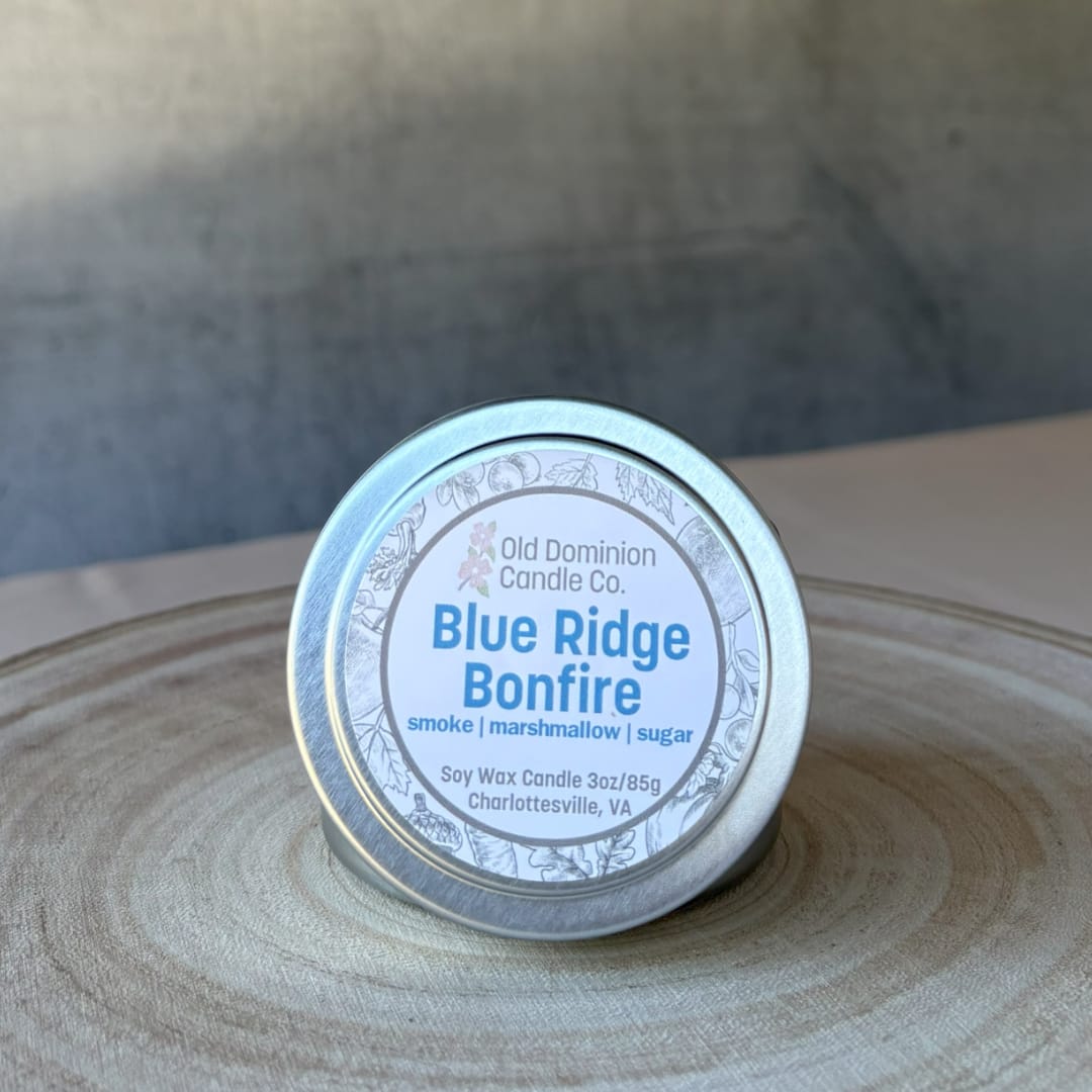 Small tin candle labeled Blue Ridge Bonfire on a wooden surface