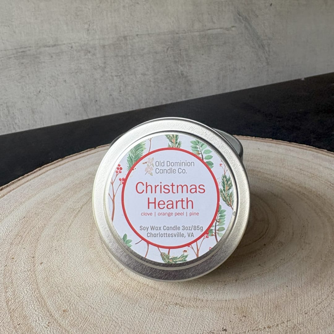 Tin candle labeled Christmas Hearth on a wooden surface