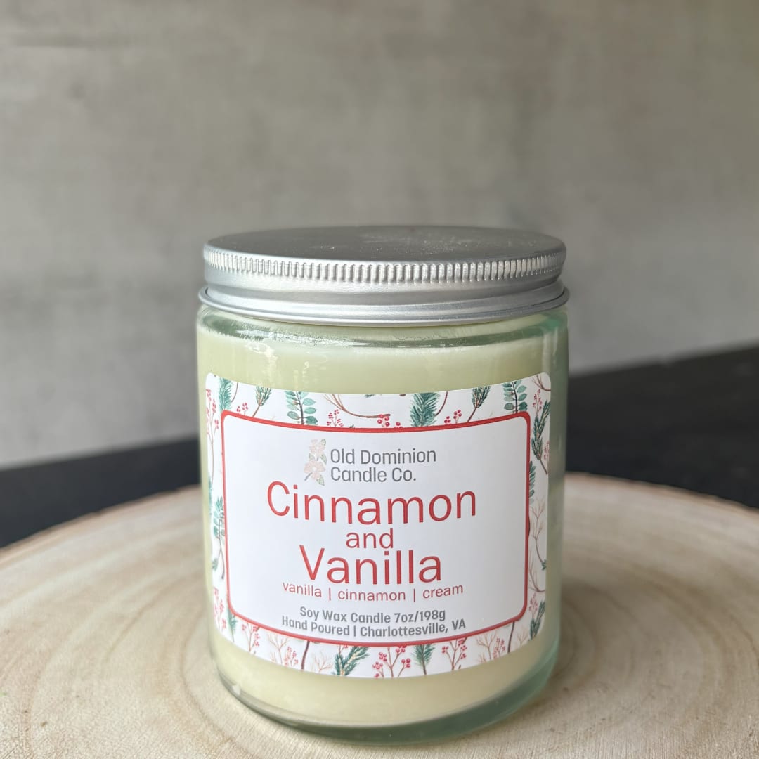 Jar candle labeled cinnamon and vanilla on a wooden surface