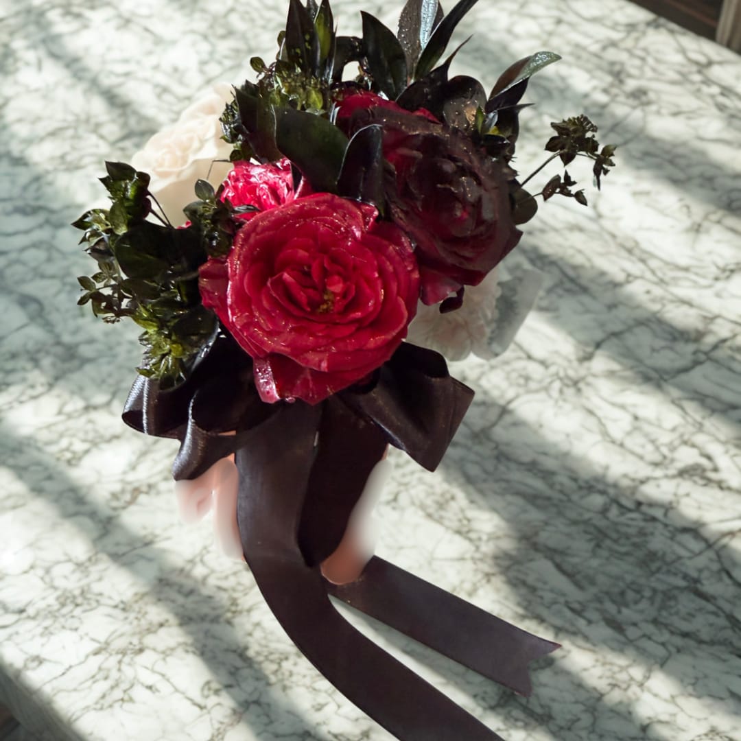 Small bouquet of red and dark roses with a black ribbon