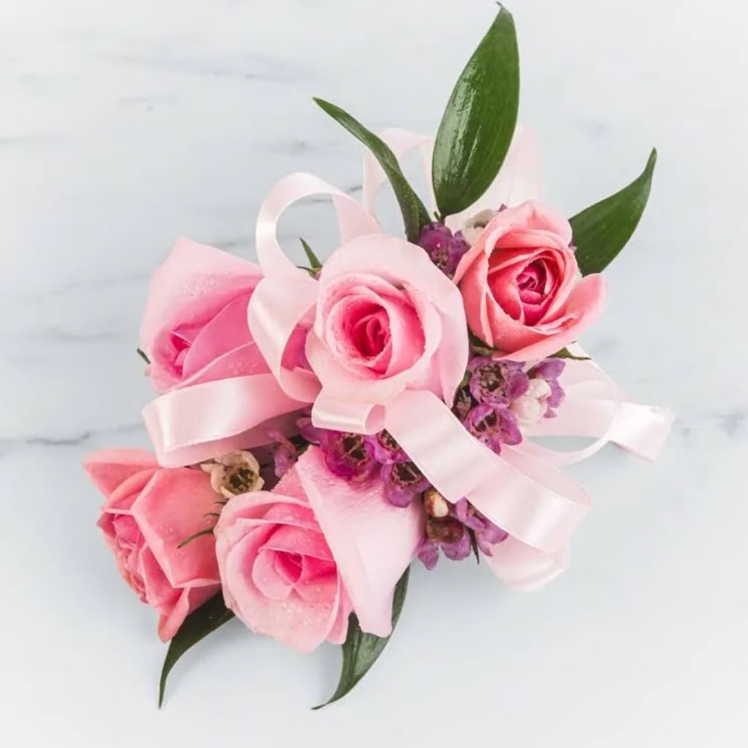Pink rose corsage with ribbon and small purple accents