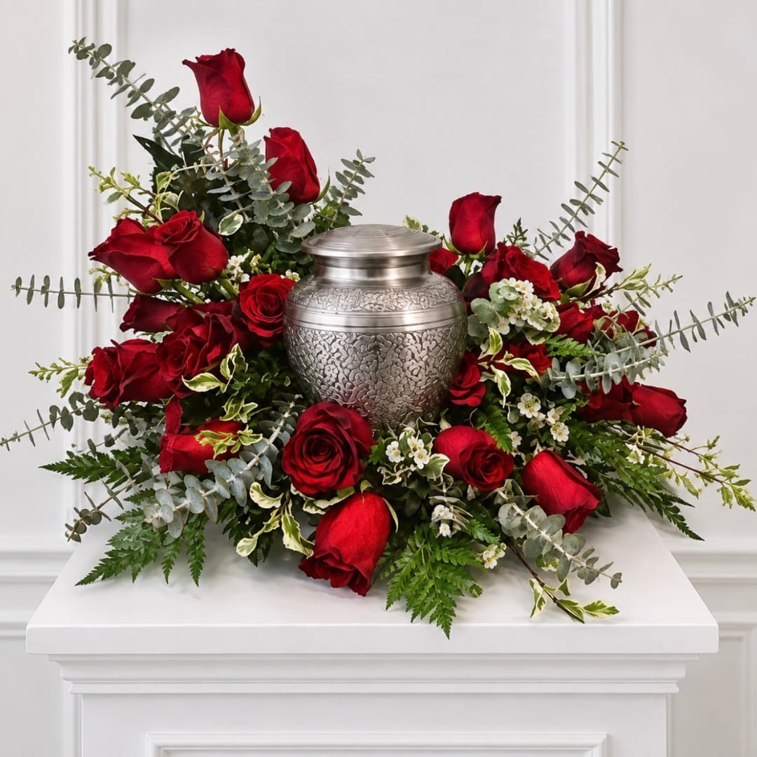 Red roses arranged around a silver urn on a white pedestal