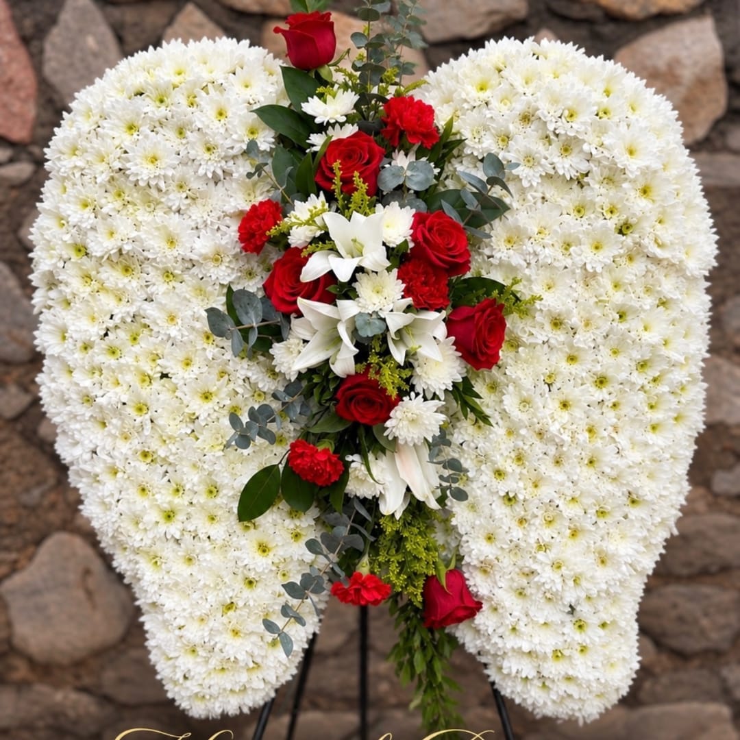 Heart-shaped white floral wreath with red roses and lilies