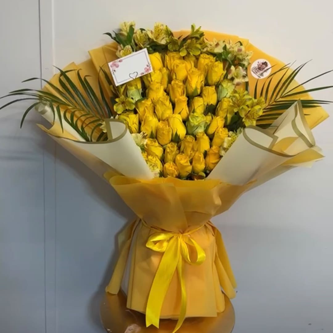 Yellow rose bouquet wrapped in yellow paper with a ribbon
