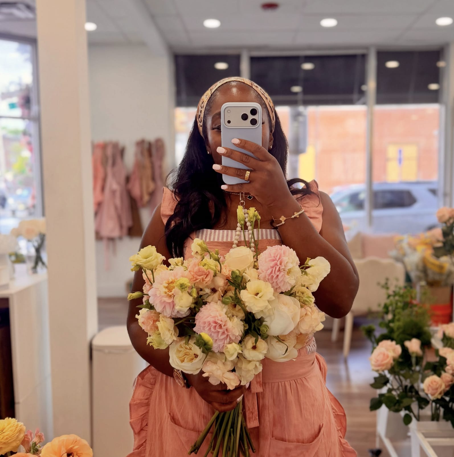 Woman holding a pastel bouquet of roses and carnations in a flower shop