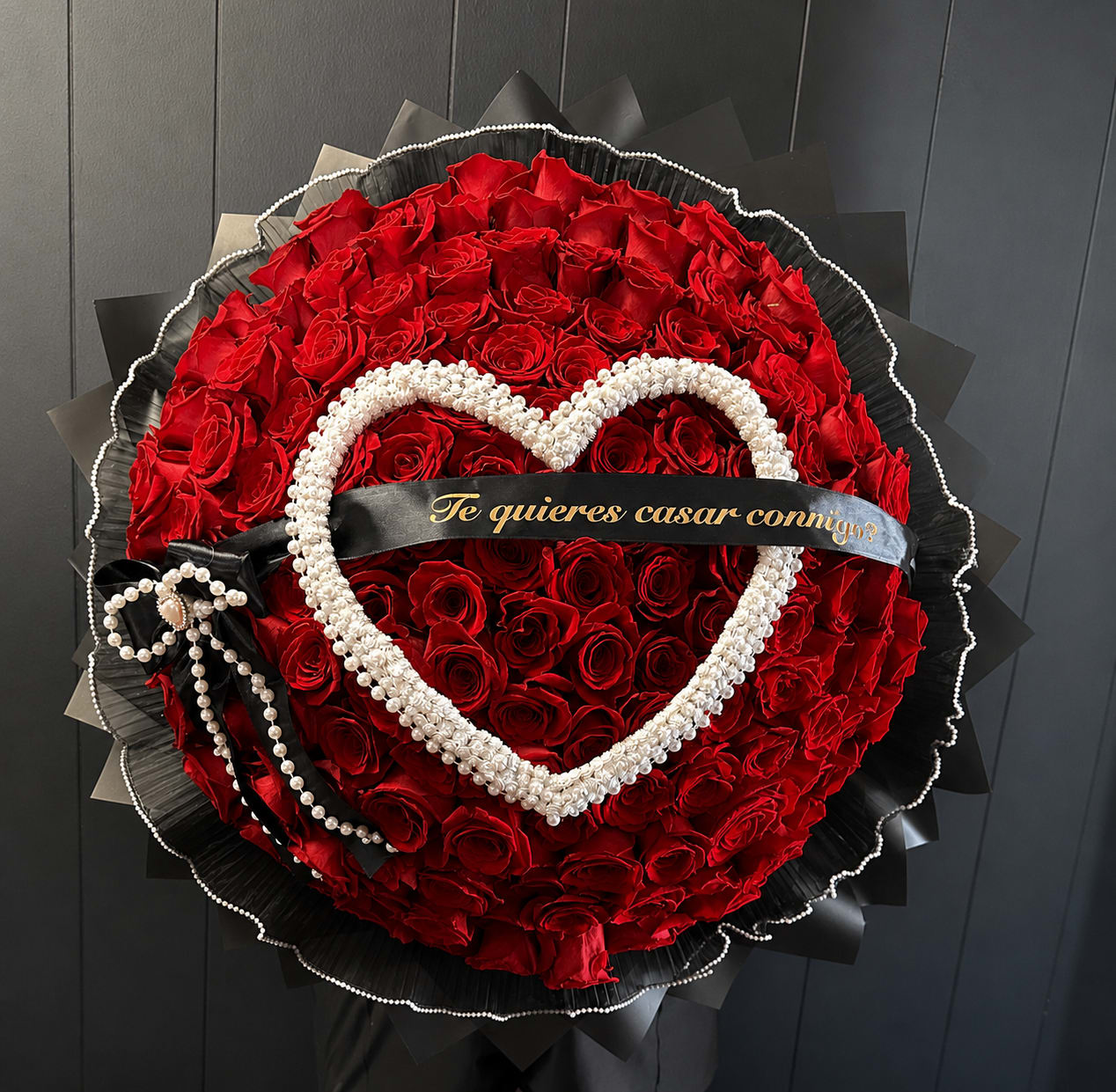 Round bouquet of red roses with a pearl heart and black ribbon