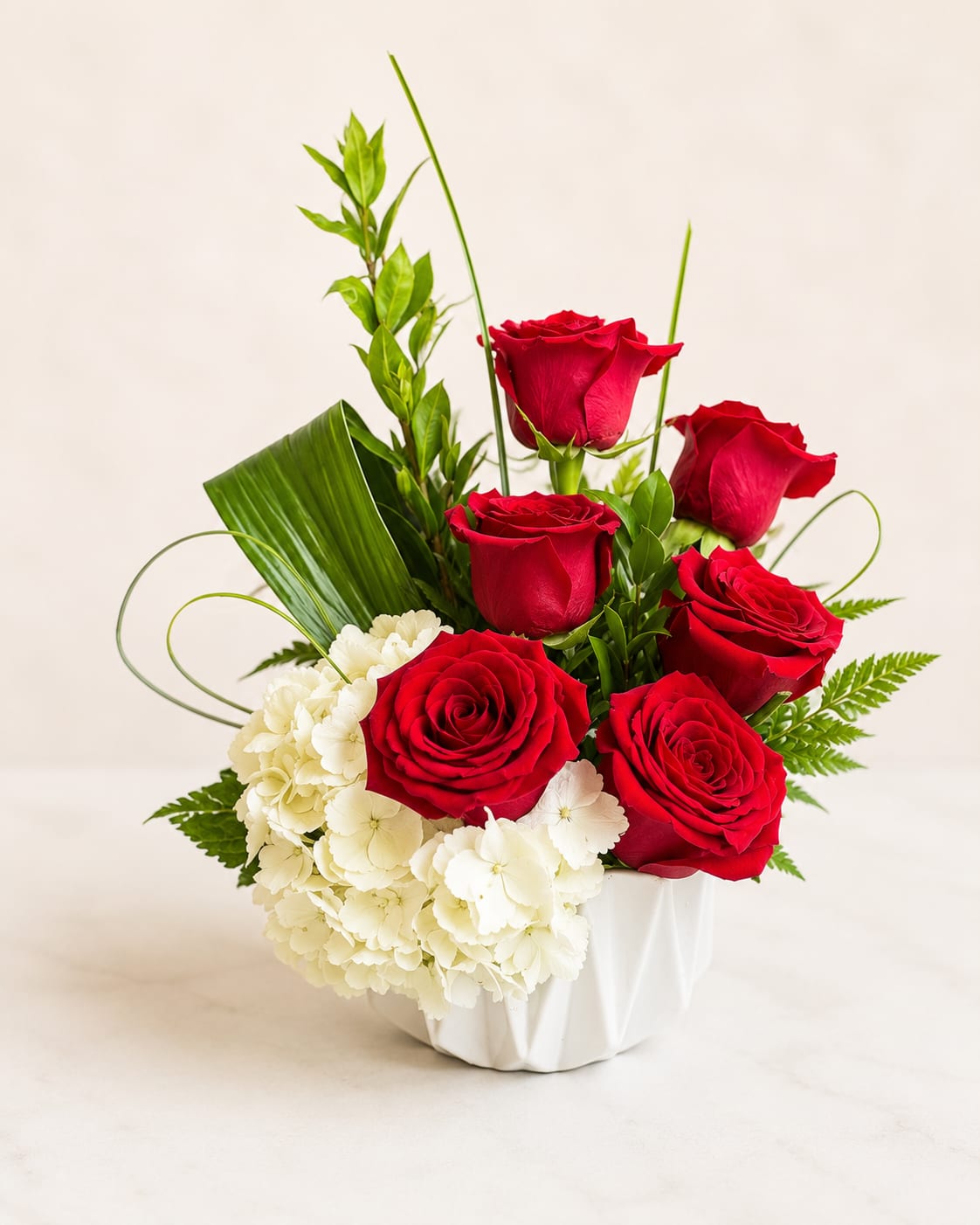 Red roses and white hydrangeas in a white vase