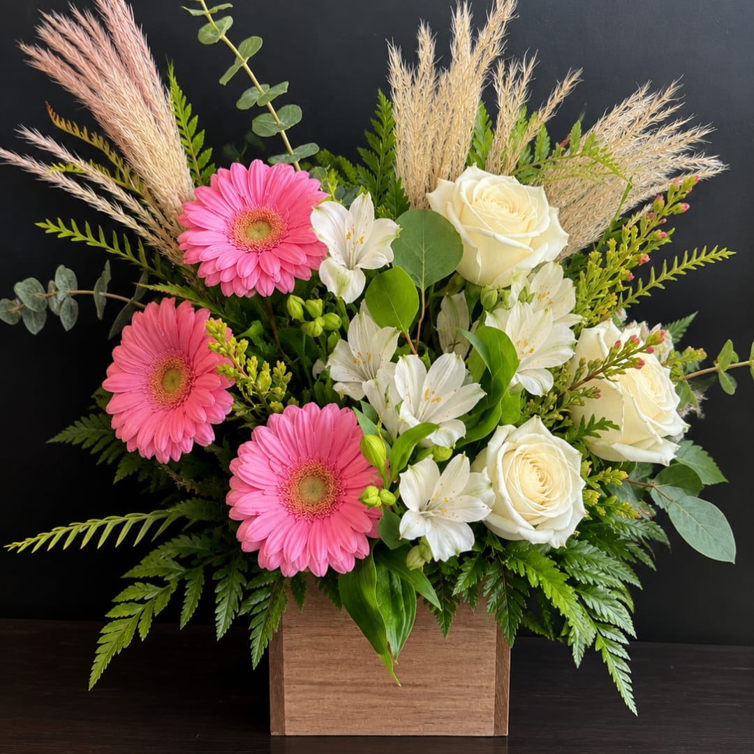 Pink gerberas and white roses in a wooden box with greenery.