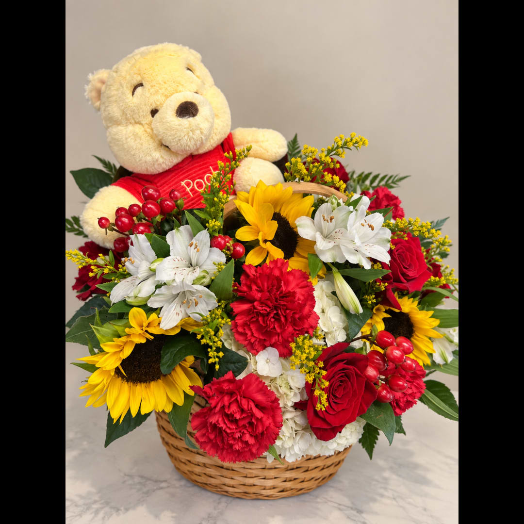 Basket arrangement with a teddy bear and mixed red, yellow, and white flowers