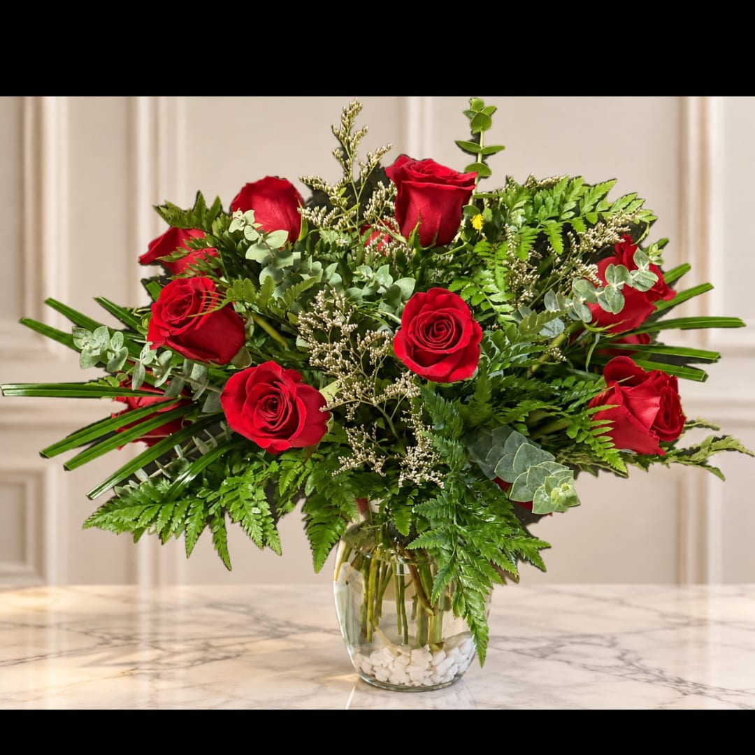 Red roses in a clear glass vase with lush greenery