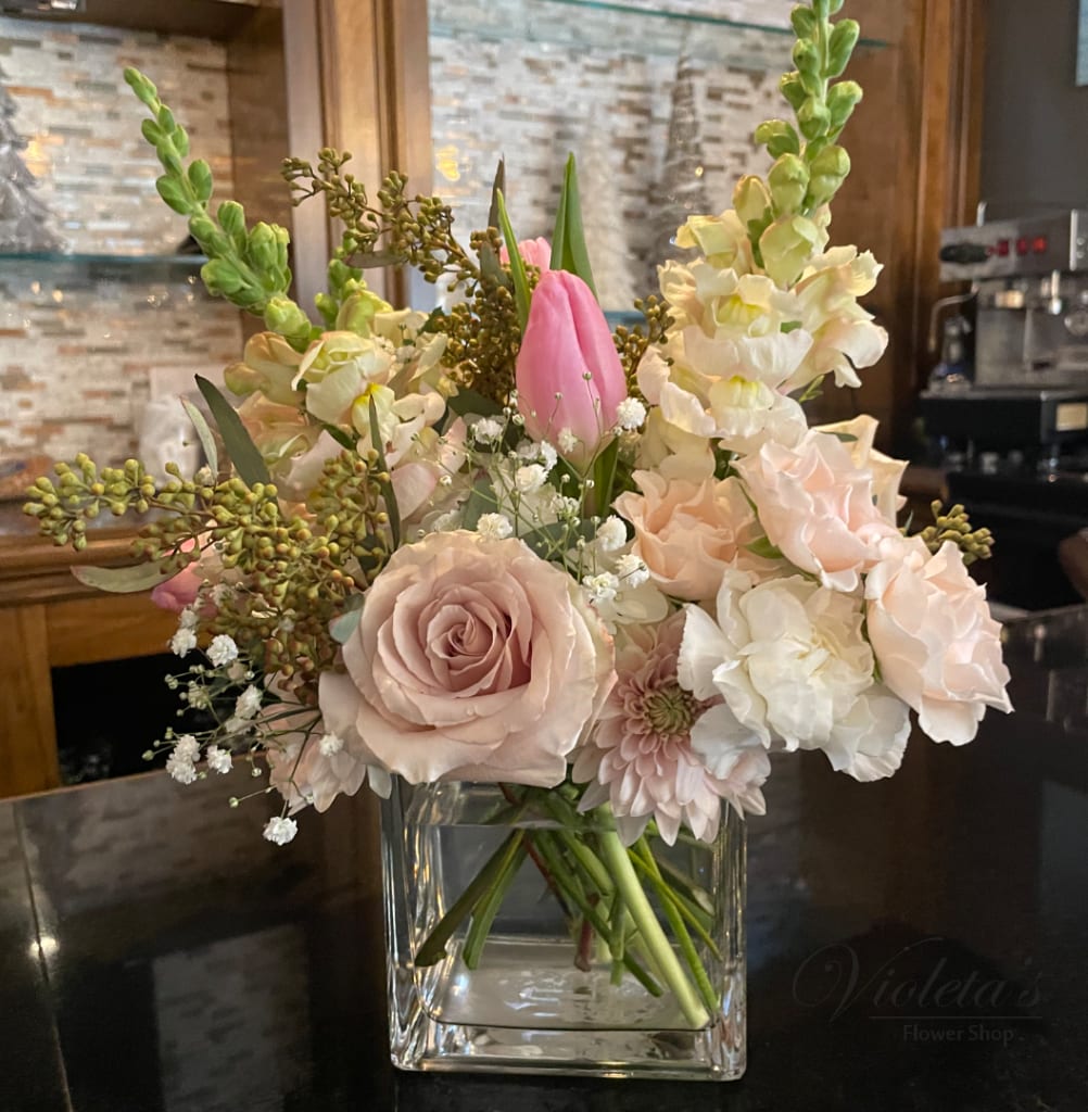 Pink and white floral arrangement in a clear square vase