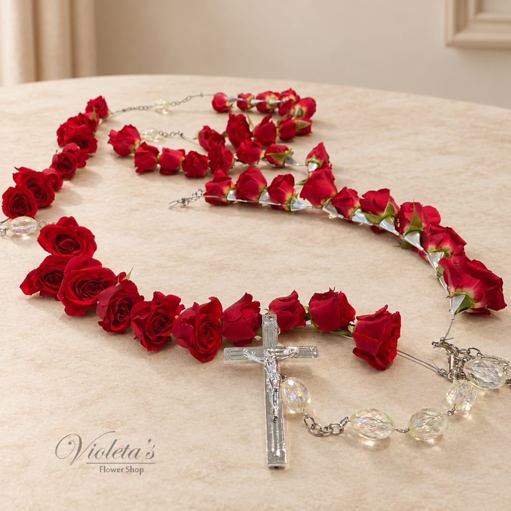 Red rose rosary with clear crucifix and bead accents on a table.