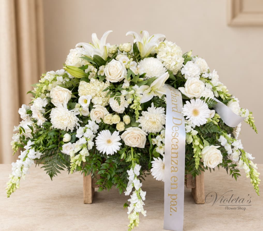 White floral arrangement with roses and lilies in a low wooden stand