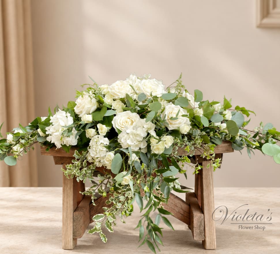 White rose arrangement with cascading greenery on a wooden stand