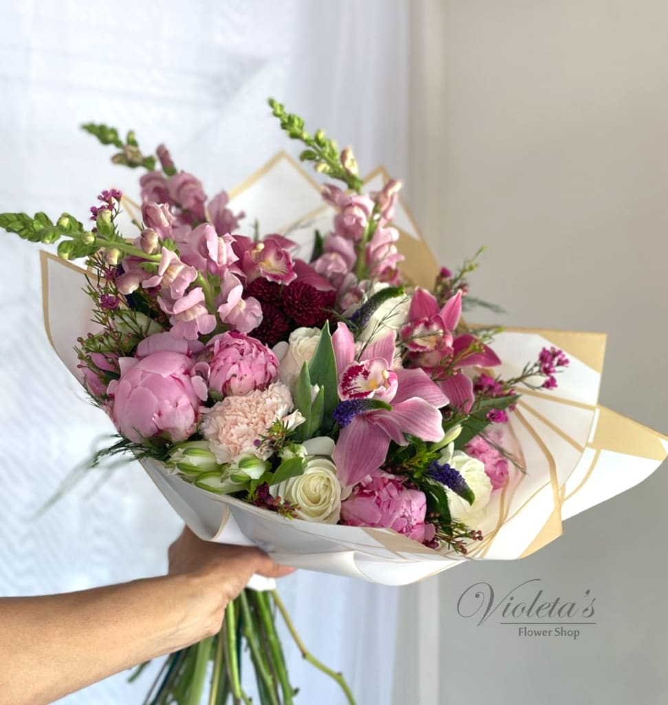 Handheld bouquet of pink and white flowers wrapped in white paper