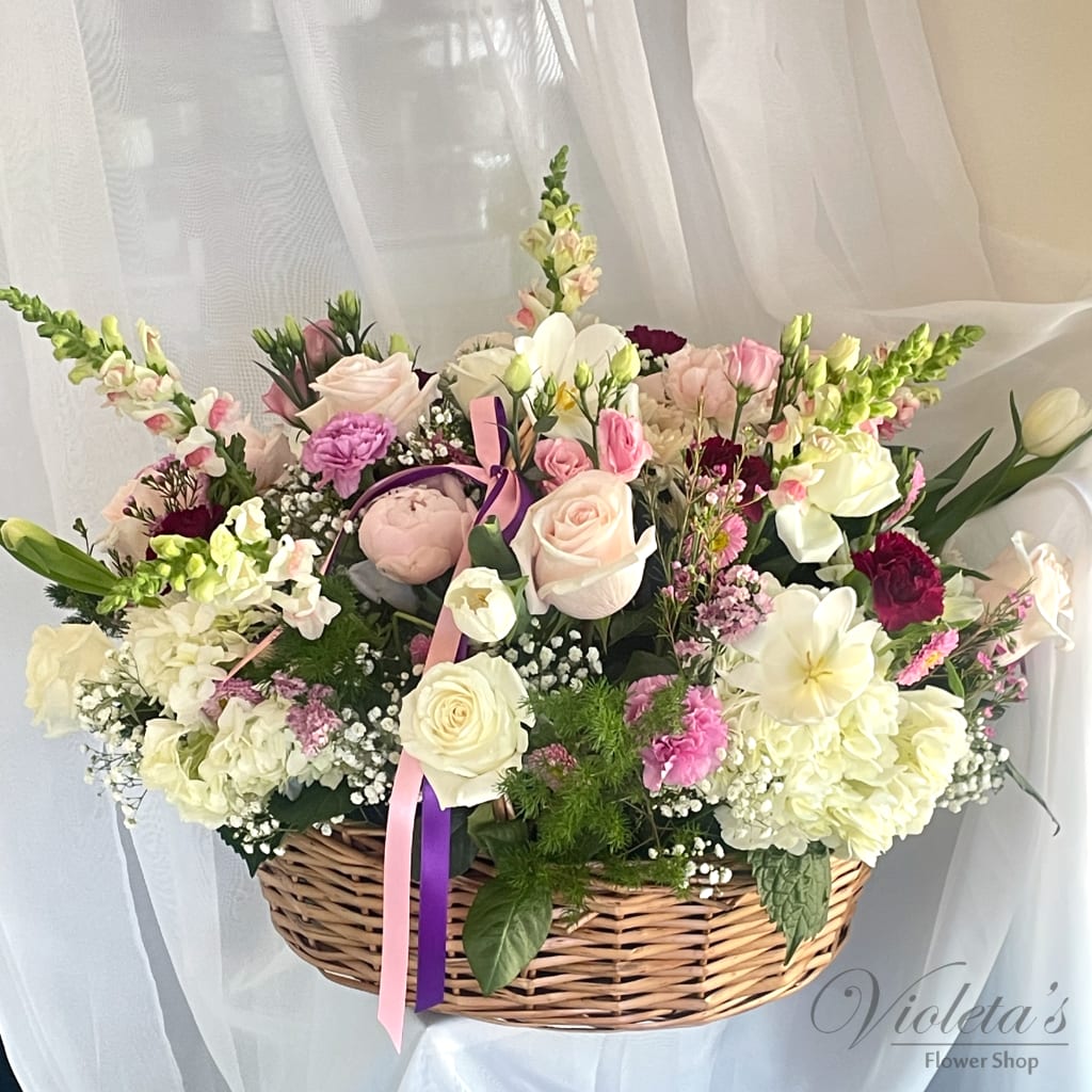 Basket arrangement of pink and white flowers with ribbon accents
