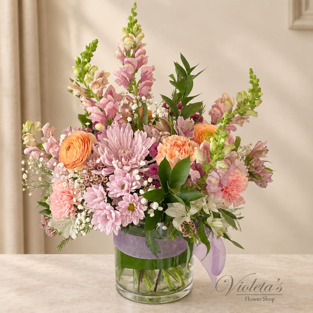 Pastel mixed bouquet in a clear glass vase with a lavender ribbon