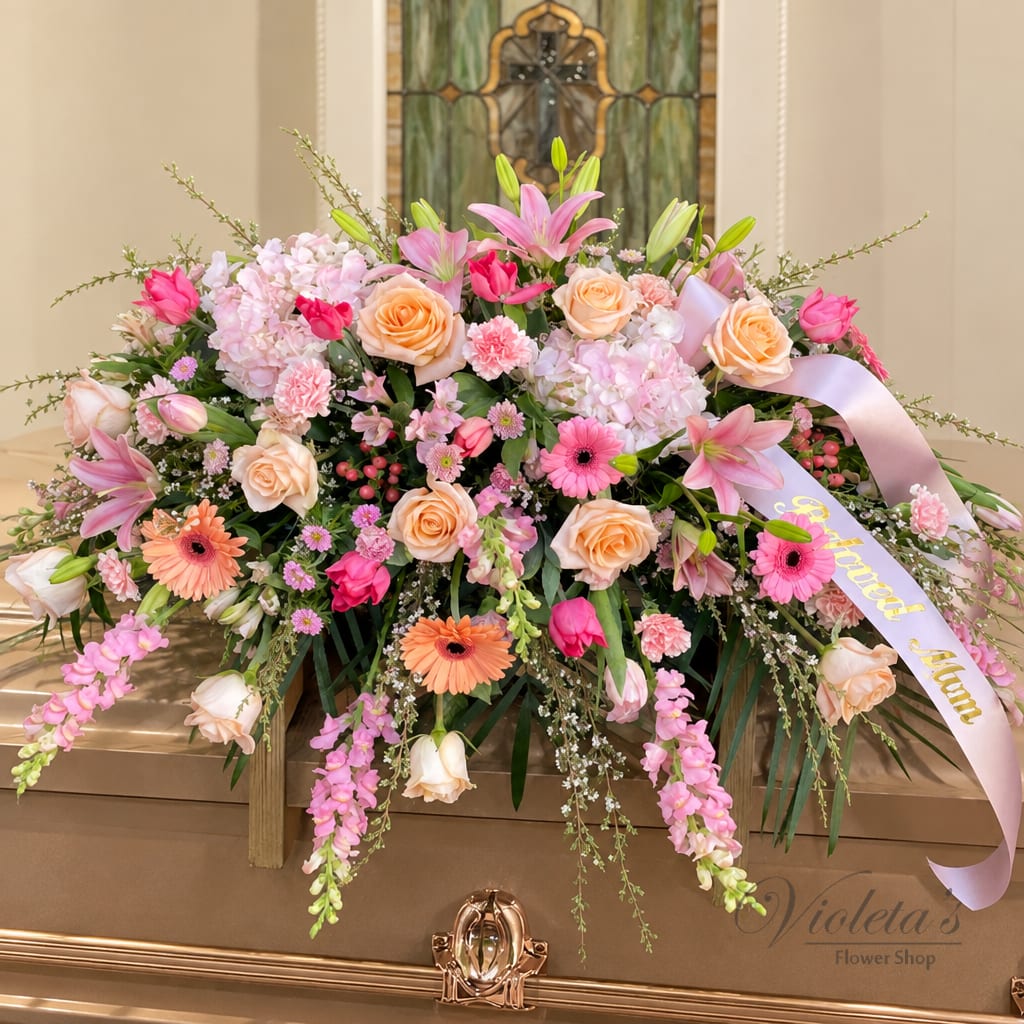 Large pink and peach floral spray with a lavender ribbon on a casket