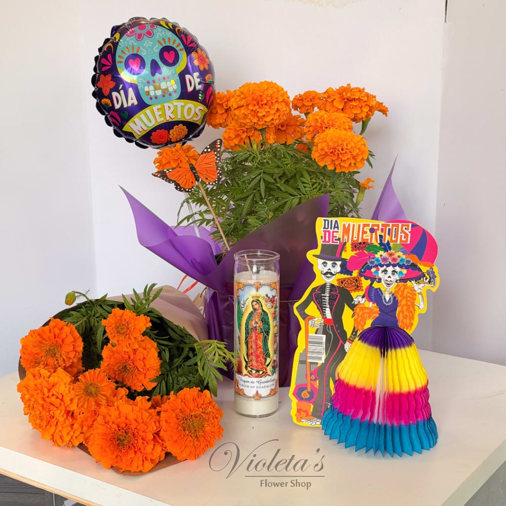 Orange marigold arrangements with Día de Muertos decorations and a candle