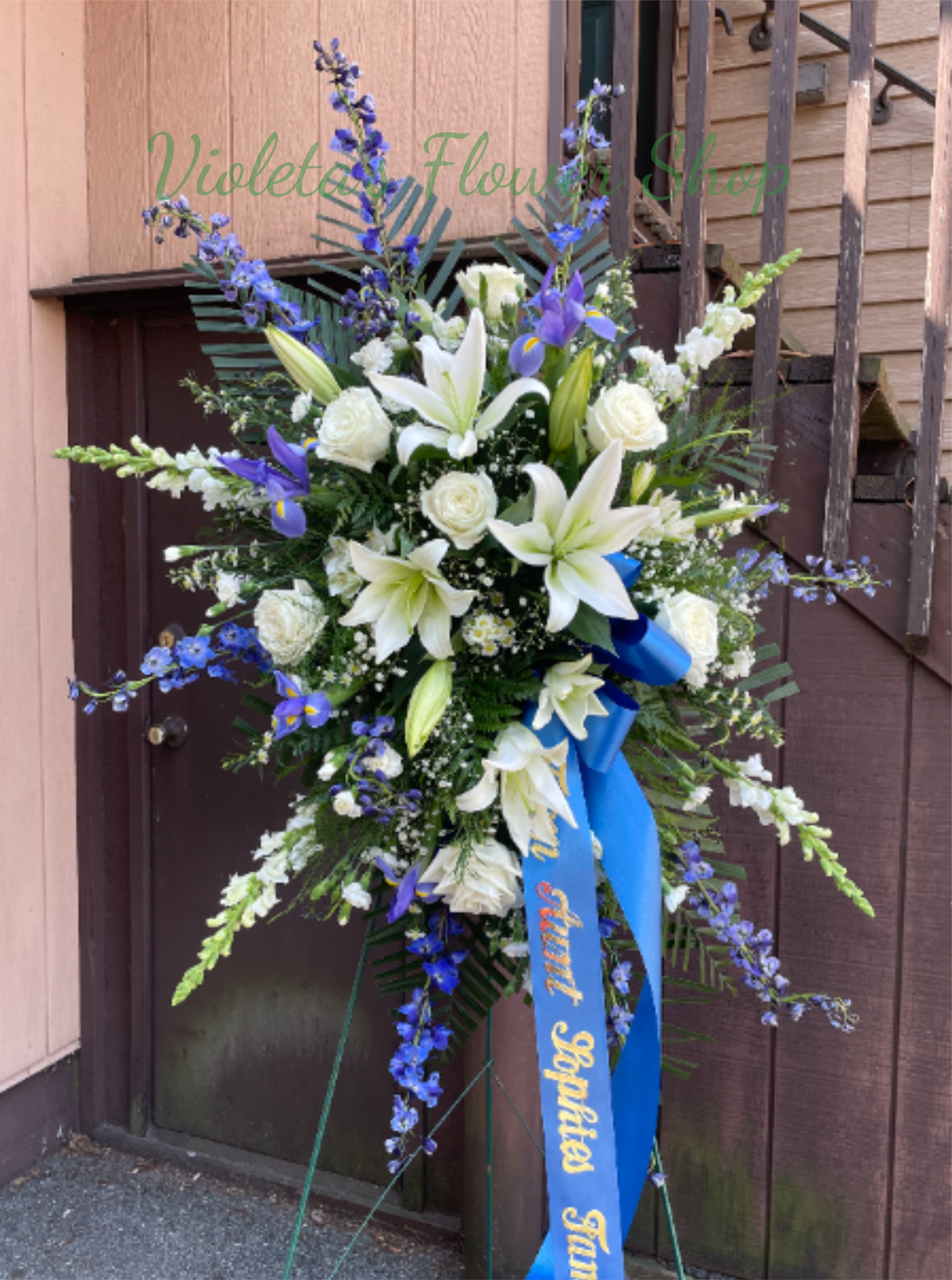Standing floral spray with white lilies, white roses, and blue flowers