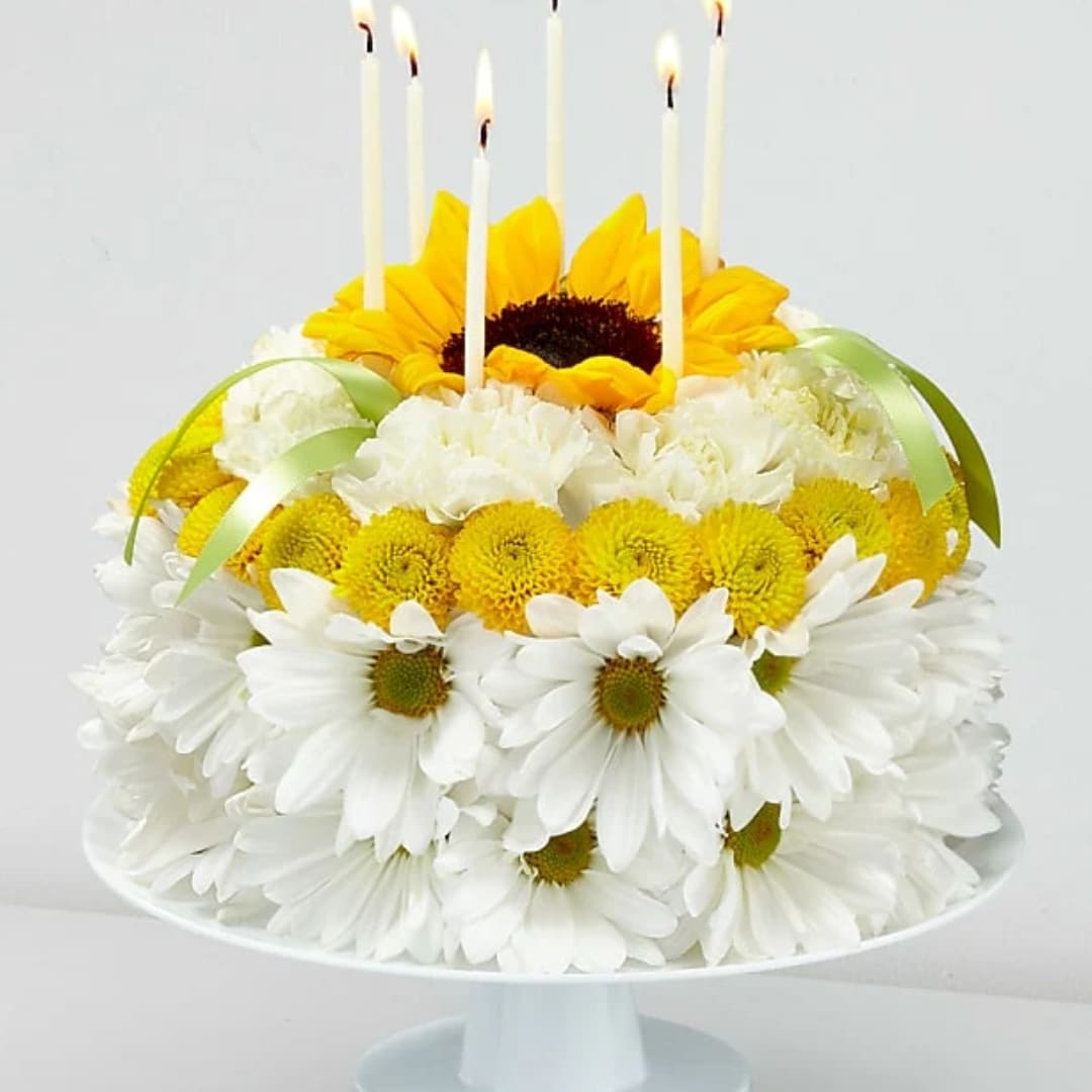 Sunflower and white daisy arrangement with lit taper candles on a pedestal stand