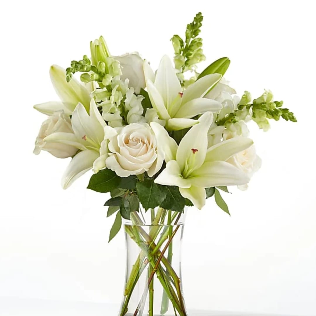 White lilies and roses arranged in a clear glass vase