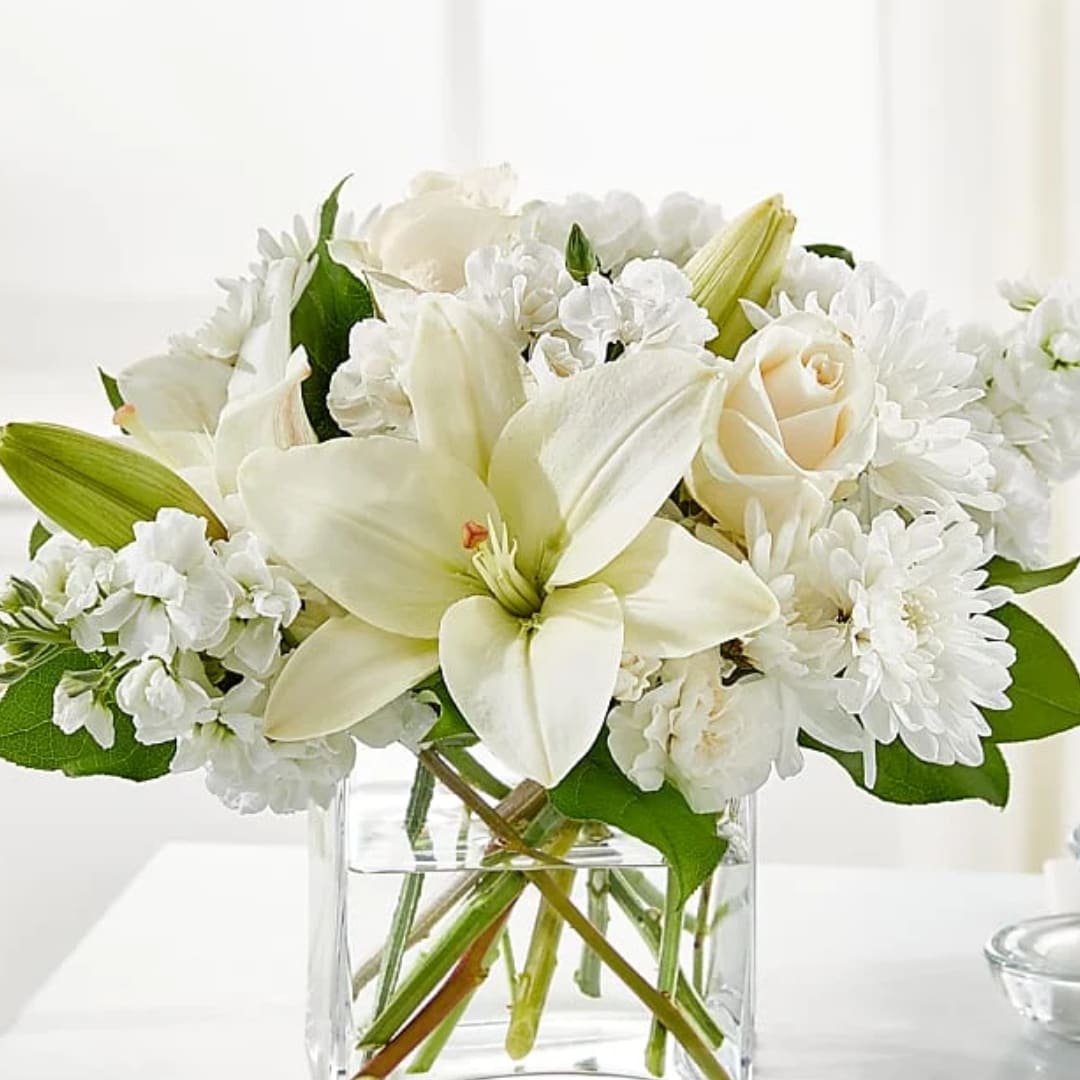 White lilies and roses arranged in a clear glass vase