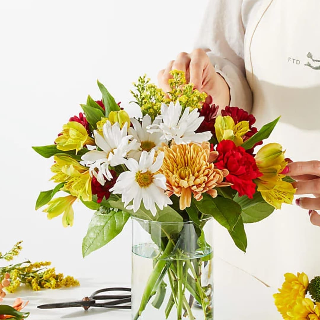 Mixed bouquet of daisies, chrysanthemums, and alstroemeria in a glass vase