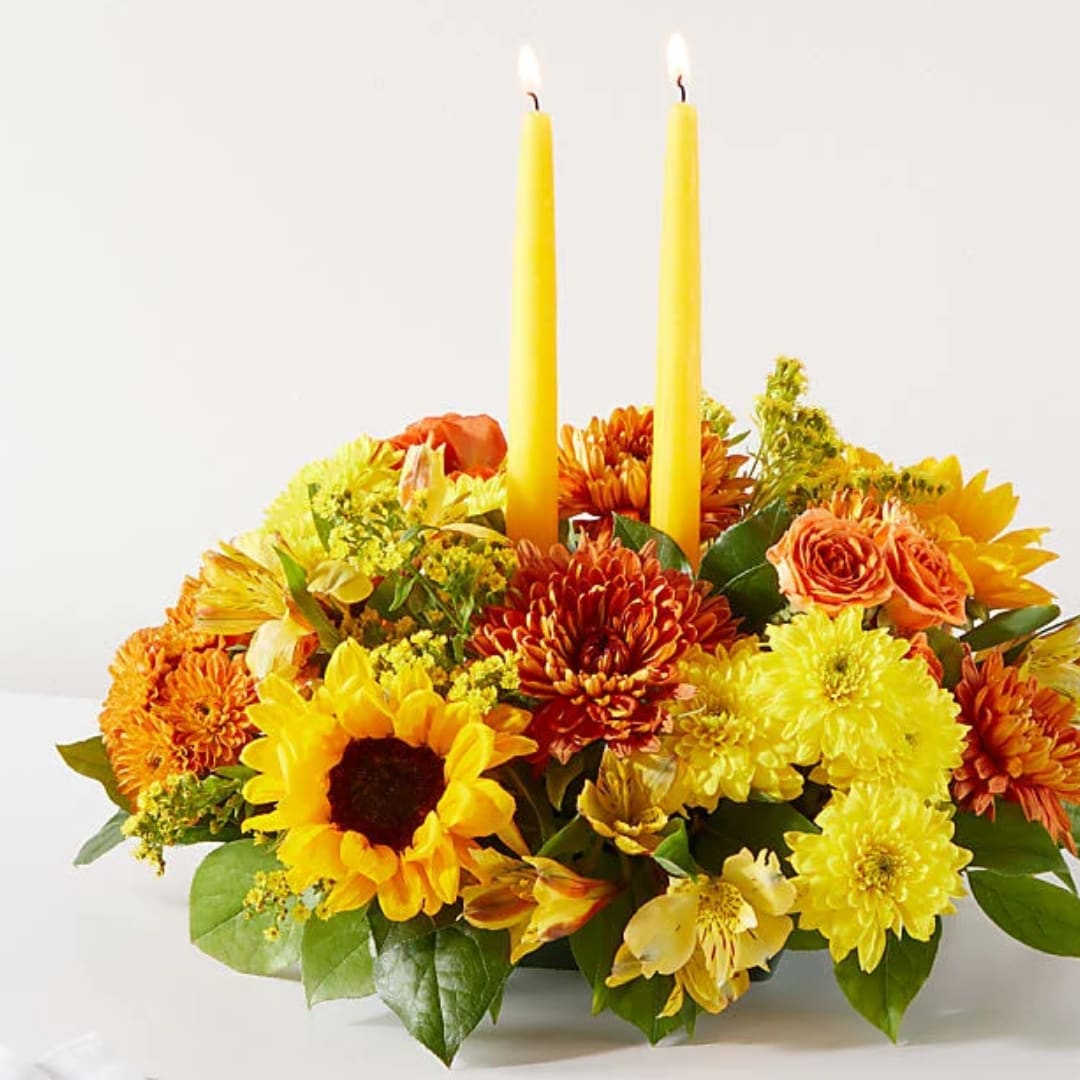Yellow and orange floral centerpiece with two tall candles