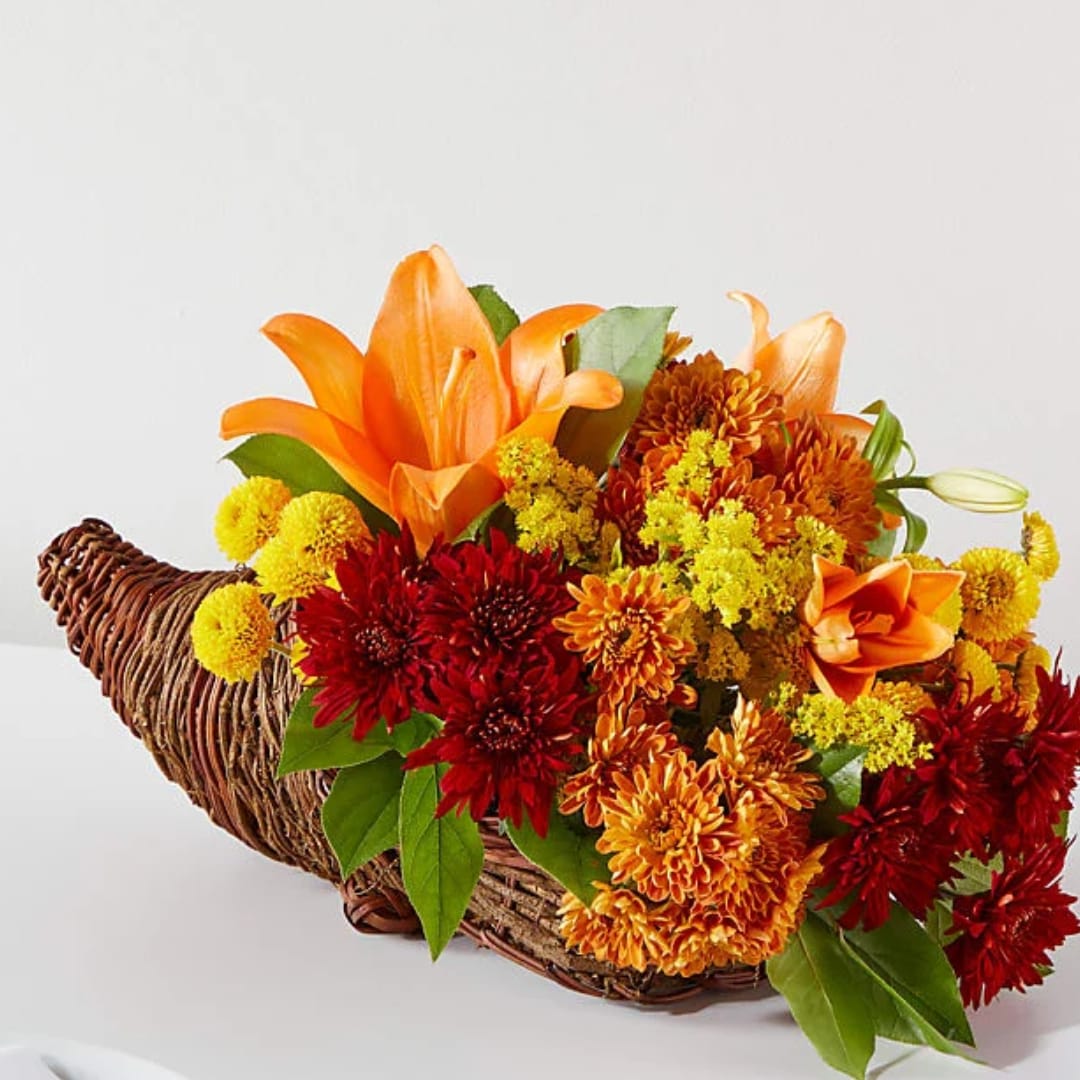 Orange lilies and red-yellow mums in a woven cornucopia basket