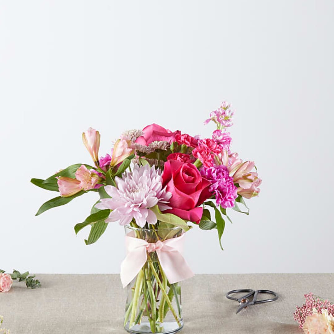 Pink and white mixed bouquet in a clear glass vase with a ribbon
