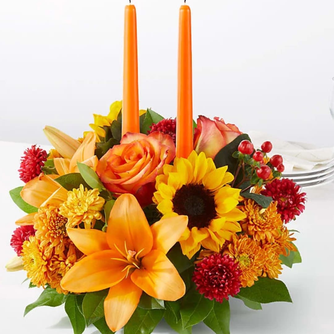 Orange floral centerpiece with two tall orange candles