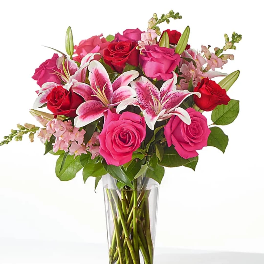 Bouquet of pink and red roses with lilies in a clear glass vase